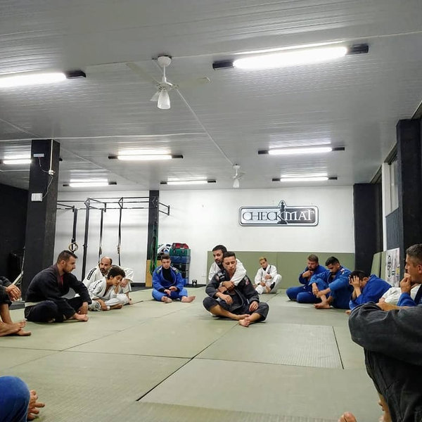 Professor orientando alunos durante aula de jiu-jitsu