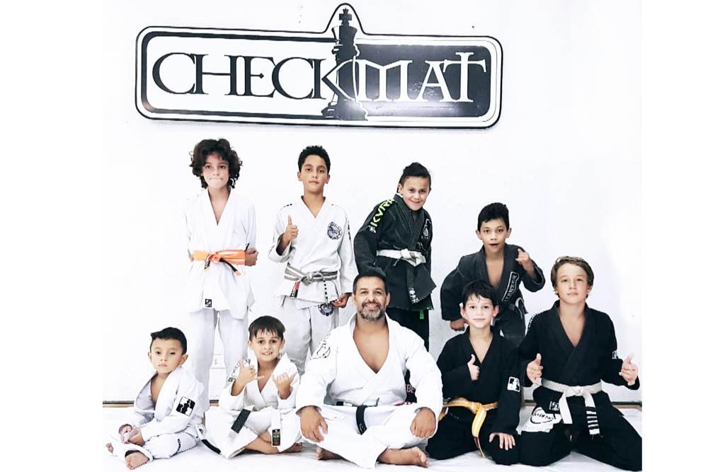 Alunos da turma kids reunidos com o professor no tatame